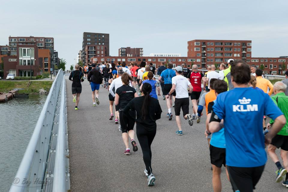 Deelnemers lopen in een lange rij over een brug tijdens de Hardloopavond4daagse van 2015.