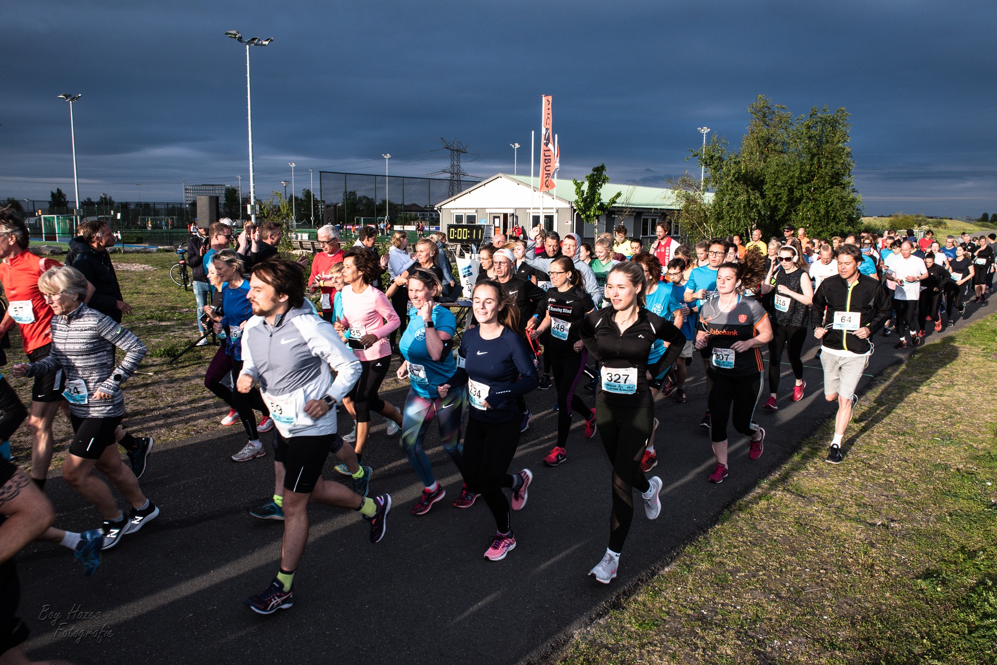 Een grote groep hardlopers loopt in avondlicht over het parcours tijdens de editie van 2019.