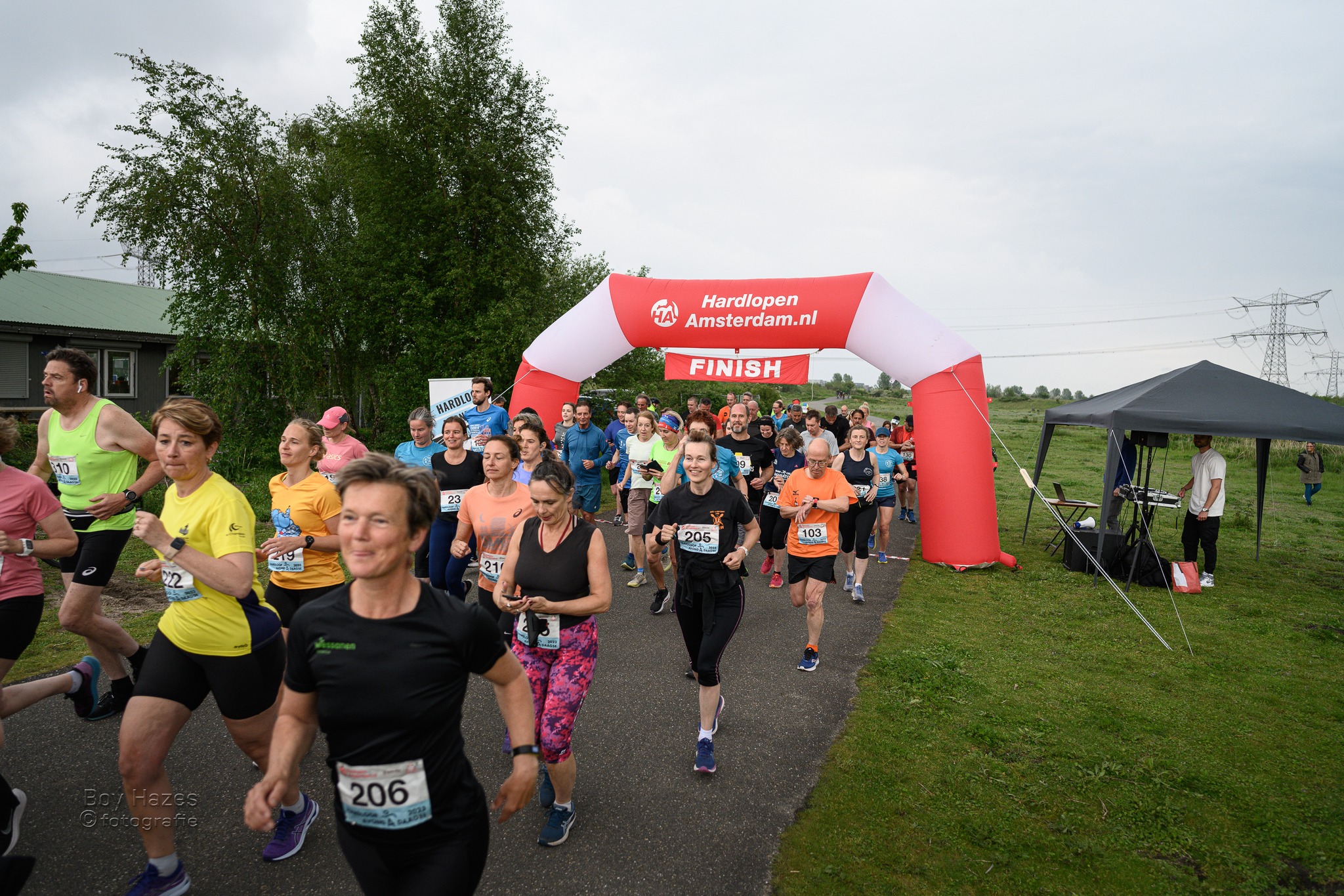 Deelnemers passeren de rode finishboog tijdens de Hardloopavond4daagse van 2023.