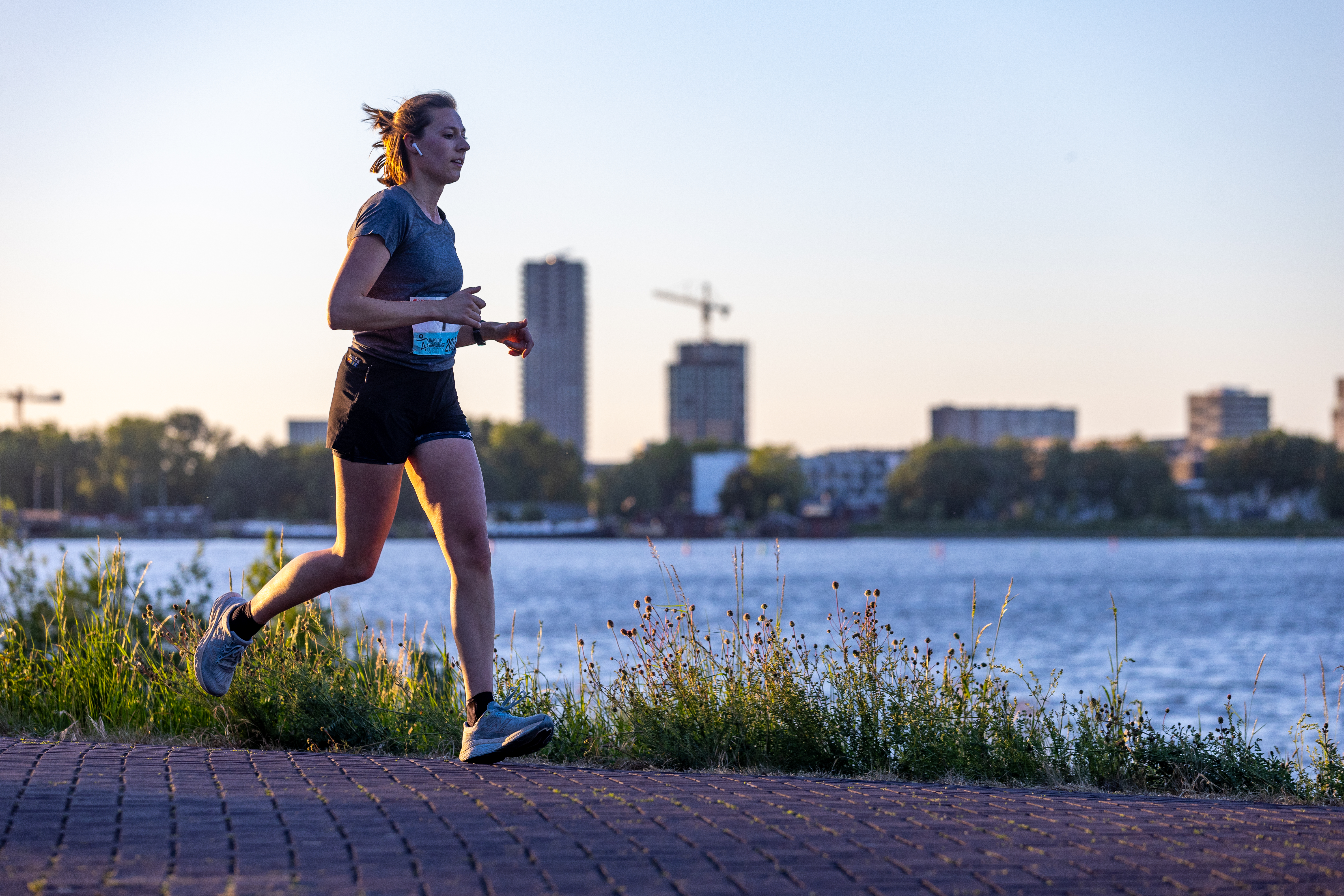 Een hardloopster loopt alleen over het pad langs het water.