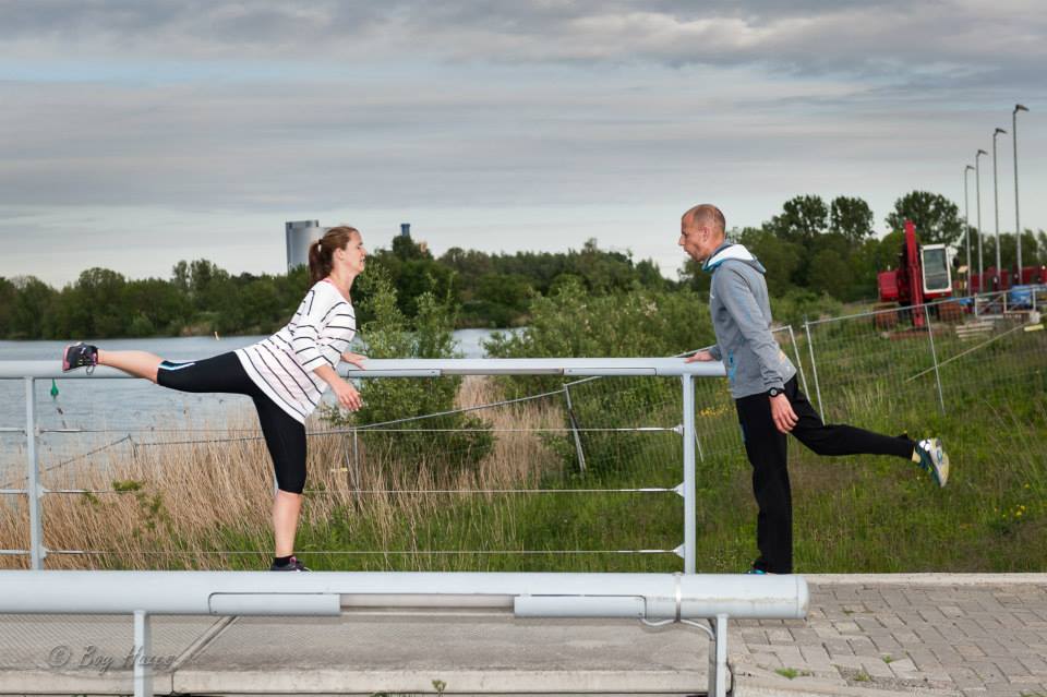 Twee deelnemers doen een balansoefening tijdens de warming-up.