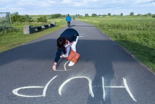 Een vrijwilliger schrijft 'HUP' met krijt op het parcours om deelnemers aan te moedigen.